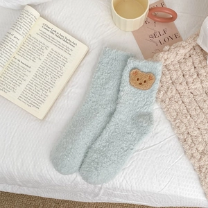 Close-up of soft light blue coral fleece socks with cute brown bear embroidery detail
