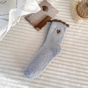 Detailed close-up of light blue coral fleece socks with brown embroidered heart and ruffle trim