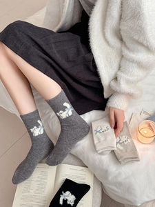 Détail de chaussettes en laine avec motif de chat 3D en gris, blanc et tons kaki