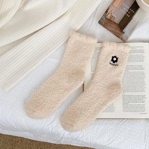 Close-up of soft white coral fleece socks featuring 3D floral embroidery and pearl accents