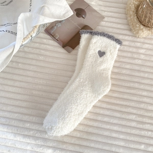 Detail of white coral fleece sock featuring a gray heart embroidery and warm plush texture