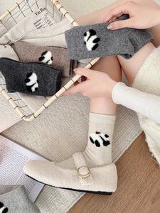 Dettaglio di calze di lana invernali con motivi panda jacquard in quattro colori caldi