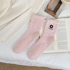 Detail showing pink coral fleece socks with delicate flower embroidery and soft pearl accent