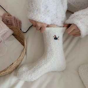 Close-up of white plush coral fleece socks featuring a delicate dachshund dog embroidery
