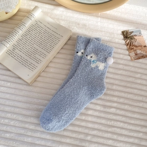 Close-up of thick light blue coral fleece winter socks with cute cartoon animal patterns
