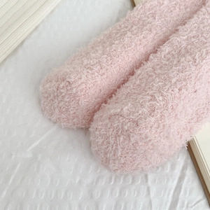 Close-up of soft pink coral fleece socks with thick curly texture and floral details