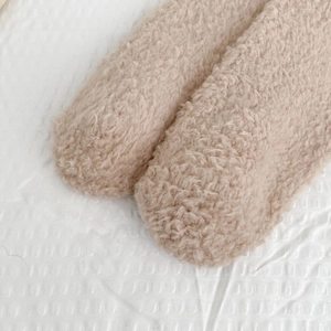 Close-up of soft beige coral fleece socks featuring thick warm sherpa texture details