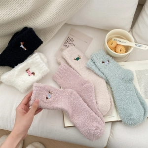 Detailed view of colorful coral fleece socks with cute dog embroidery on a sofa