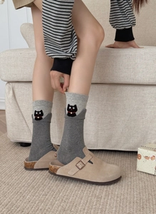 Detail of grey knit sock featuring an adorable black cat pattern and red collar accent