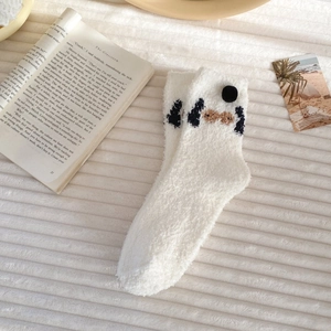 Close-up of white fluffy coral fleece socks with cute cartoon puppy pattern detail