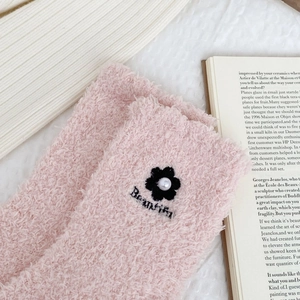 Close-up of pink coral fleece socks with flower embroidery and pearl detail