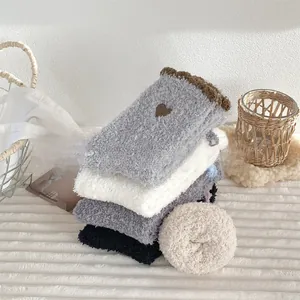 Close-up of cozy coral fleece socks with heart embroidery in assorted soft colors