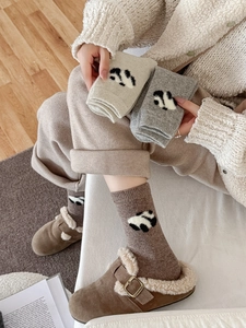 Dettaglio di calze di lana con spessa trama a maglia e simpatico motivo panda 3D