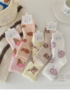 Detailed view of soft coral fleece socks with cute cartoon patterns and paper tags