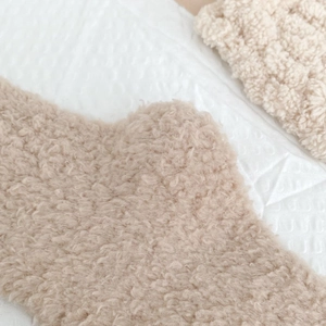 Close-up of soft coral fleece texture on warm beige thermal fuzzy winter socks