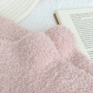 Macro detail of soft pink coral fleece socks showing thick fuzzy texture and plush fibers