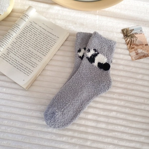 Close-up of grey coral fleece socks with panda design on a cozy white fleece background