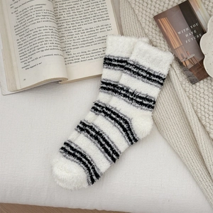 Close-up of black and white striped coral fleece socks on a cozy winter blanket
