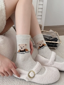 Gros plan sur les chaussettes en laine gris clair à motif d'ours et chaussons doux