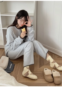 Detail of coral fleece loungewear set with thick warm socks on a wooden floor