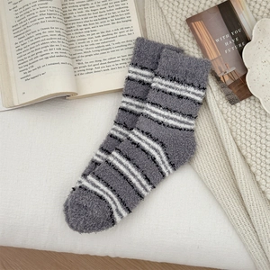 Close-up of cozy grey striped coral fleece socks on a decorative home background