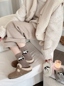 Dettaglio del ricamo panda su spesse calze invernali in lana nei colori marrone e grigio
