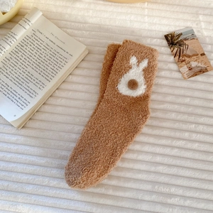 Detail of warm brown coral fleece socks with 3D pom-poms and cute rabbit patterns