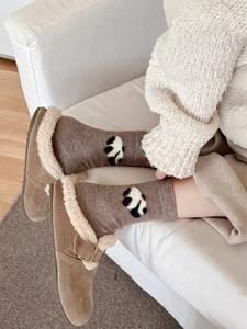 Dettaglio di calze di lana con panda e pantofole in pelle scamosciata foderate in pile