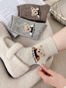 Détail de chaussettes en laine avec broderie ours en peluche et texture tricotée épaisse