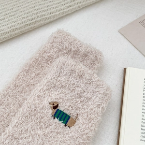 Close-up of cute dachshund dog embroidery on plush coral fleece socks for winter