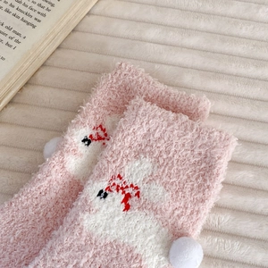 Detail of pink coral fleece socks featuring cute rabbit embroidery and soft pom pom