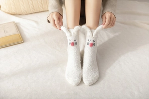 Detail showing white coral fleece rabbit socks with 3D ears and pink plush nose