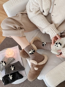 Dettaglio macro del ricamo panda su calze di lana invernali spesse in ambiente caldo