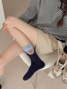 Close-up of cotton socks with cartoon bear pattern and ribbed cuffs on model legs