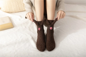Close-up of fluffy dark brown bunny socks with 3D ears and soft coral fleece texture
