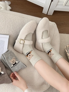 Détail de chaussures en peluche crème avec chaussettes en laine vertes brodées d'ours