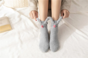 Detail of plush grey bunny slipper socks with 3D ears and soft coral fleece texture