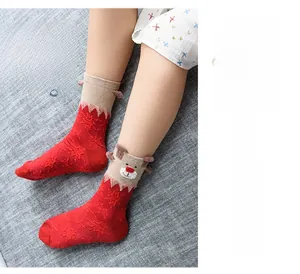 Detail of red Christmas socks featuring 3D elk motifs and white snowflake patterns