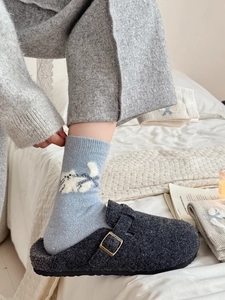 Détail de sabots en feutre gris foncé avec boucle et chaussettes bleues motif chat