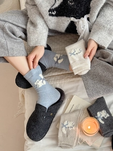 Gros plan de chaussettes en laine d'hiver avec motifs de chats tricotés et nœuds colorés
