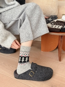 Cozy Fair Isle wool socks with Christmas patterns and felt clogs on wooden floor