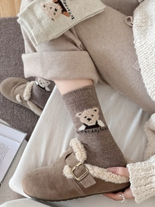 Détail de chaussettes en laine à broderie ours et pantoufles en cuir fourrées