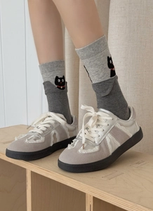 Close-up of cute black cat embroidery on grey crew socks with lace trim sneakers
