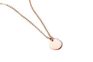 Macro view of polished rose gold round pendant necklace with a minimalist smooth finish