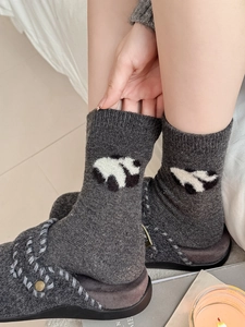 Dettaglio di calze spesse in lana grigio scuro con motivi panda jacquard per l'inverno