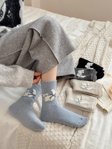 Détail de chaussettes en laine avec broderie de chat et bords-côtes aux tons doux