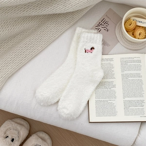 Detail of white fluffy coral fleece socks featuring cute dachshund dog embroidery