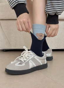 Detail of blue knitted socks featuring cute brown bear embroidery and layered cuff design