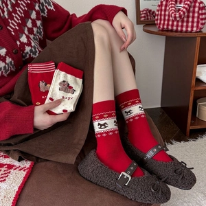 Detail of red festive crew socks featuring knit horse and apple patterns in soft cotton