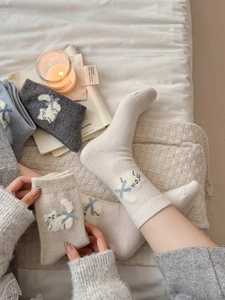 Détail de chaussettes en laine montrant la maille épaisse et broderie de chat au nœud bleu